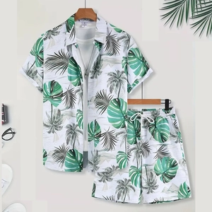 Flat lay of tropical palm print summer shirt and shorts set with beach accessories