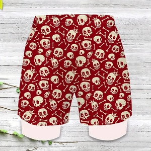 Detail of red men's beach shorts featuring white skull and crown prints with elastic waistband