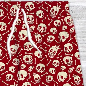 Detail of red shorts with skull prints and a white textured drawstring on wood background