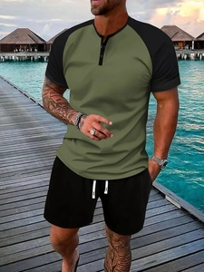 Outdoor shot of men's green Henley t-shirt and black shorts set on a beach boardwalk