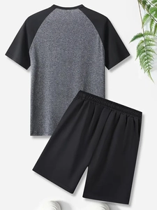 Flat lay of men's two-piece athletic set with grey raglan tee and black shorts
