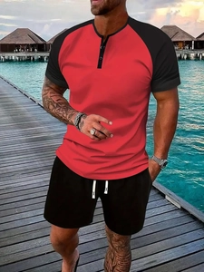 Close-up of men's red and black henley neck T-shirt and drawstring shorts on a beach