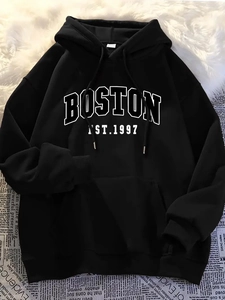 Flat lay of black hoodie with white Boston print on textured newsprint background
