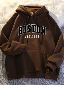 Close-up of brown hoodie with Boston embroidery on cozy white faux fur and newspaper background