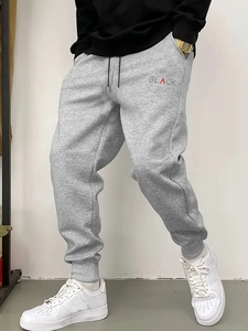 Detail of men's grey jogger pants with black drawstring and red accent letter print
