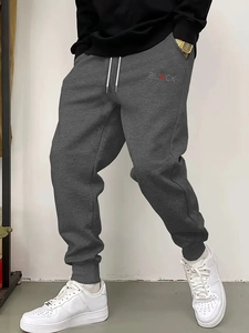 Detail of dark grey joggers with BLACK lettering, drawstring waist, and ribbed cuffs