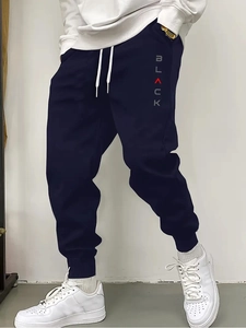 Detail of dark blue joggers featuring white drawstring waist and vertical BLACK printed logo