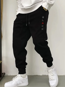 Detail of men's black joggers showing drawstring waist and vertical BLACK graphic print