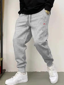 Detail of grey joggers with drawstring waist and vertical text print on the thigh