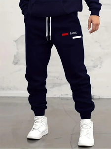 Detailed view of navy blue joggers featuring white Paris text print and drawstrings