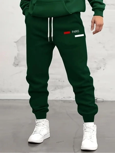 Detail of dark green men's joggers featuring Paris logo print and elasticated cuffs