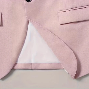 Close-up of pink blazer detailing a black button, flap pocket, and smooth white lining