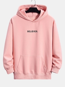 Detailed close-up of pink hooded sweatshirt featuring black BELIEVER text and rib cuffs