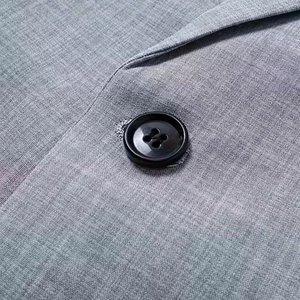 Detailed macro view of black four-hole button and textured grey woven fabric on suit jacket