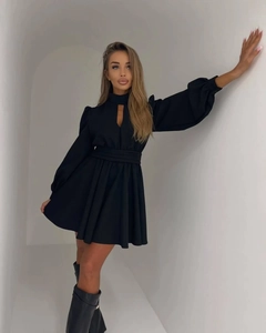 Detail of a black mini dress featuring a keyhole neckline, lantern sleeves, and a cinched waist