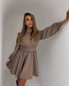 Detail of the stand-up collar with teardrop cutout and pleated waist on a tan mini dress