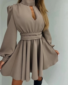 Detail view of the cut-out V-neckline and elegant pleated waist on a dark taupe dress