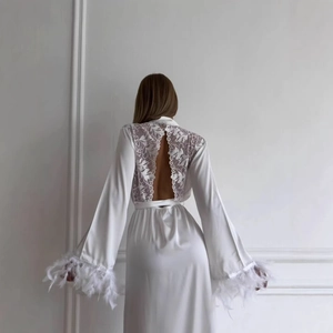 Détail de peignoir en satin blanc avec dos en dentelle florale et poignets en plumes chic