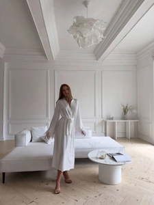 Détail d'un peignoir en satin blanc avec poignets en plumes et texture de soie luxueuse