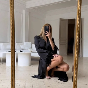Gros plan sur un peignoir en satin noir élégant avec des bordures en plumes luxueuses aux manches