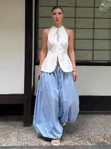 Dettaglio del top bianco all'americana con spacco e pantaloni larghi celesti stile lanterna