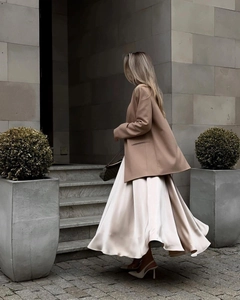 Outdoor street style showing an elegant high-waisted satin maxi skirt in cream white