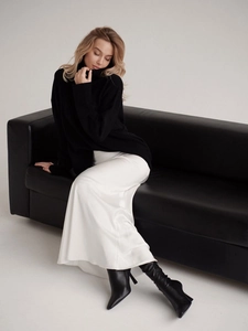 Detailed view of elegant white satin high waist maxi skirt paired with black knit sweater