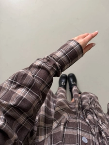 Détail de la texture d'une robe à carreaux marron avec des chaussures noires vernies