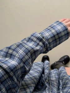 Gros plan d'une chemise à carreaux bleus et blancs montrant les boutons de manche