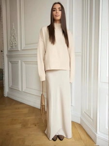 Detail view of elegant cream satin maxi skirt paired with a cozy knit sweater