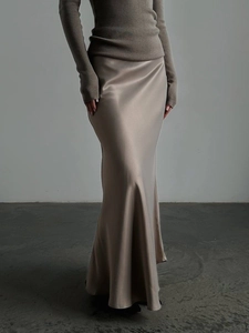 Detail of elegant satin maxi skirt showing glossy champagne texture and fluid drape