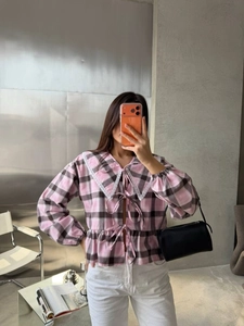Close-up of pink checkered blouse with lace collar and front ribbon bow ties
