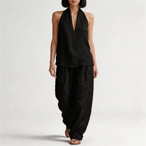 Detail of minimalist black linen two-piece set featuring halter neck top and wide leg pants