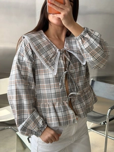 Detailed view of plaid shirt featuring lace peter pan collar and ribbon tie front