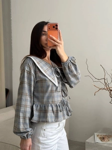 Detailed view of plaid shirt with Peter Pan collar and delicate lace trims and bows