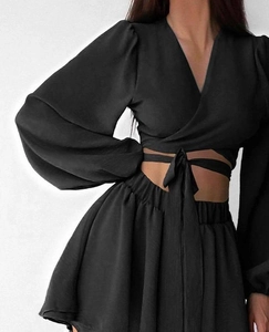 Détail d'un haut cache-cœur noir à manches longues avec ceinture et short taille haute