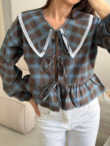 Detailed view of plaid shirt featuring vintage lace collar and bow tie closures