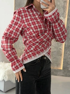 Detail of red plaid wrap shirt showing delicate white lace trim on sleeves and hemline