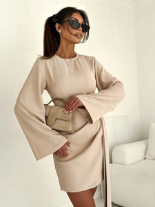 Détail d'une robe portefeuille beige avec manches cloche et rubans latéraux élégants