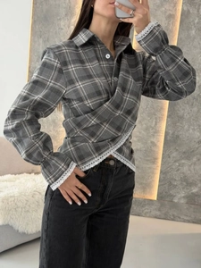 Detail of grey plaid shirt featuring crossover design and white floral lace hem and cuffs