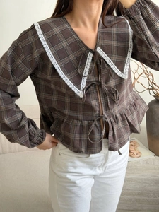 Detail of Peter Pan collar with lace trim and bow-tie closures on plaid blouse