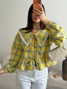 Detailed view of yellow plaid blouse with lace collar and three front bow ties