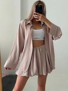 Détail d'un ensemble chemise à manches longues et jupe plissée mauve en tissu texturé