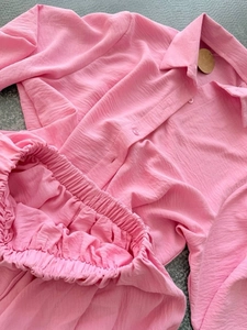 Détail d'un ensemble chemise rose à manches longues et short en tissu crépu gaufré