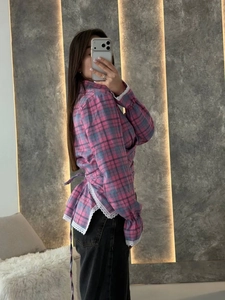 Detail view of pink and blue plaid shirt featuring lace trim hem and side tie structure