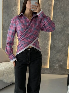 Detailed view of wrap-style plaid shirt with white lace trim and pink blue check pattern