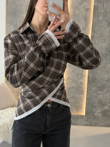 Detailed macro view of delicate white lace trim on the hem of brown plaid shirt