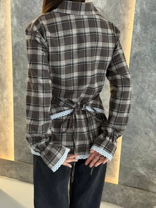 Detail of vintage plaid shirt featuring lace trim on hem and adjustable lace-up back