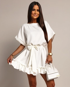 Detail of white ruffled mini dress with bow tie waist and short sleeves on model