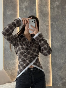 Detail view of brown plaid long sleeve shirt featuring lace trim and crossover waist design